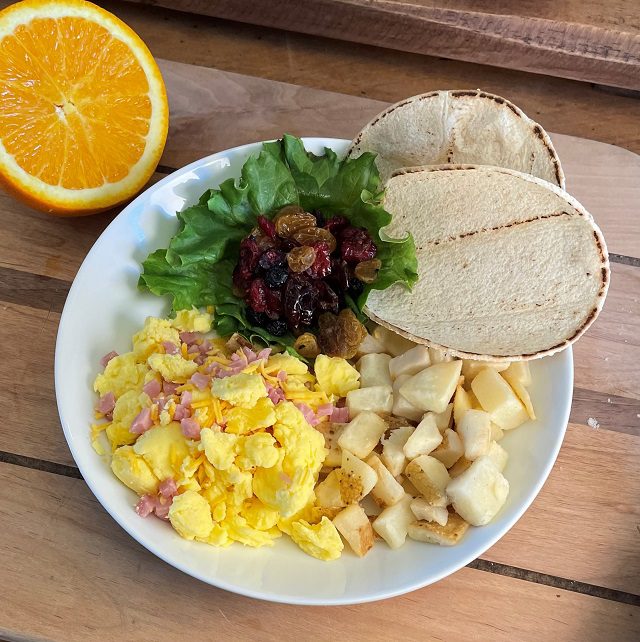 Low sodium diced ham, shredded cheddar cheese, scrambled eggs with roasted potatoes, two corn tortillas and a mixed dried fruit packet.